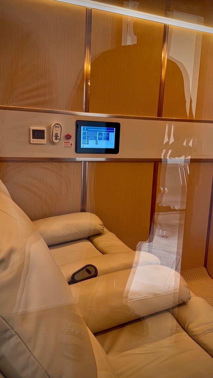 Pohled přes okno hyperbarické komory ChiroMiro na křesla a ovládací panel